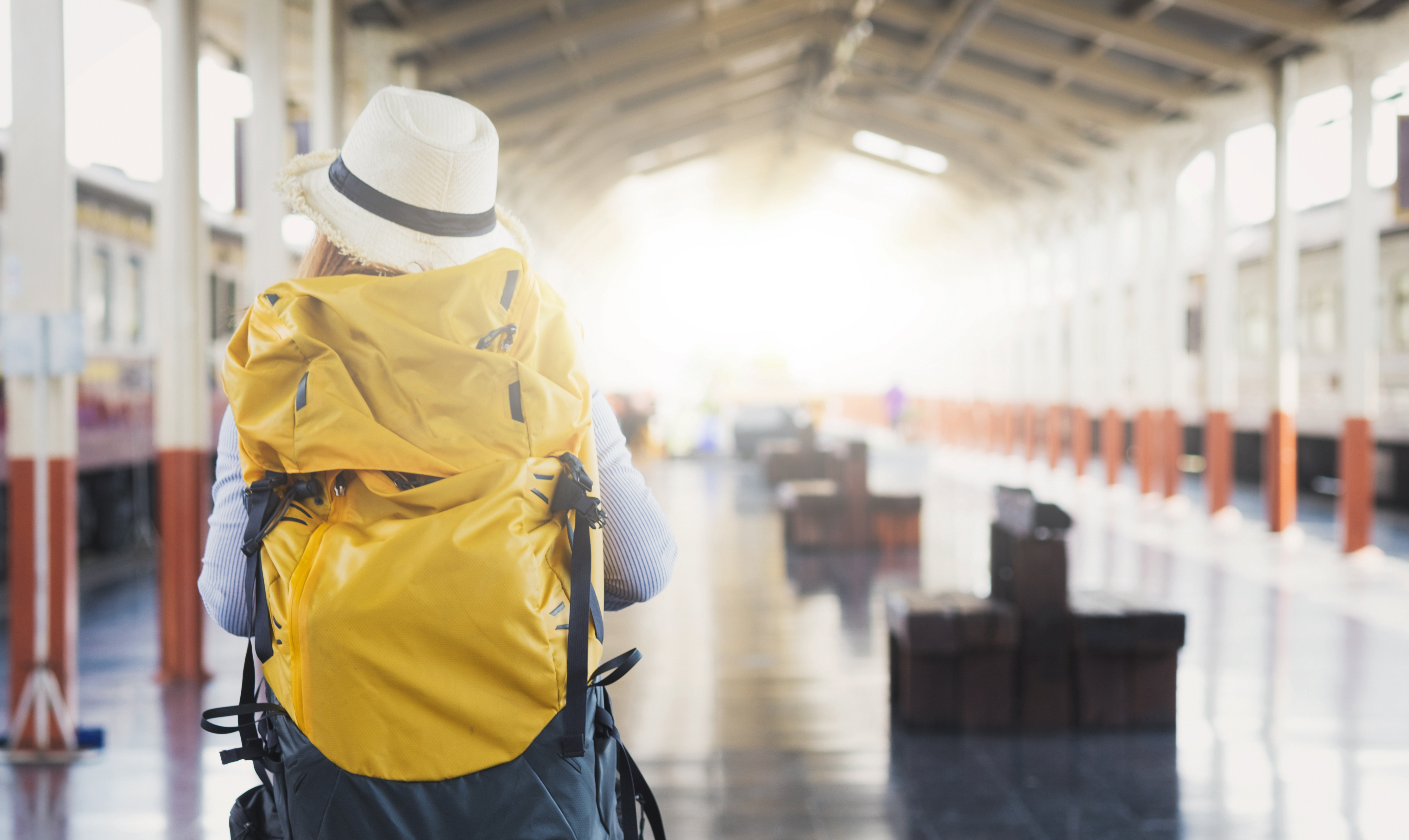 Travel concept. Backpack and hat at the train station with a traveler.